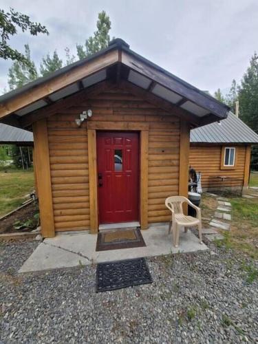 a log cabin with a red door and a chair at Sterling Cabin close to Kenai River in Sterling