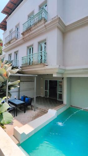 a building with a swimming pool in front of a house at Plot 77 by hnh in Baga