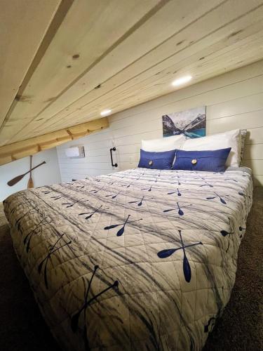 a bedroom with a large bed with blue pillows at Catch'em AK - Salmon Cove in Soldotna