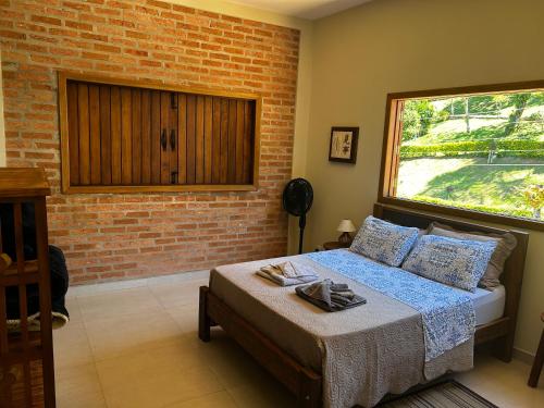 a bedroom with a bed and a brick wall at Pousada Acordes do Lago in Cunha