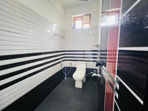 a bathroom with a toilet in a room with american stripes at HiDot Holidays in Padinjarathara