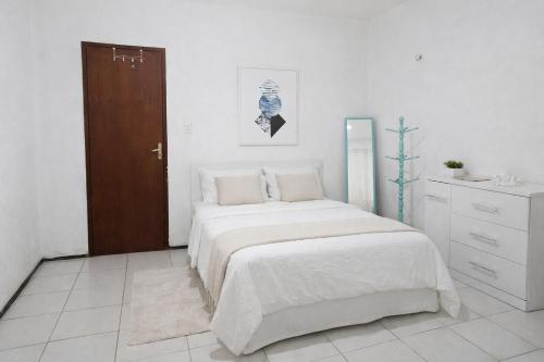a white bedroom with a bed and a wooden door at Casa da Mari in Caucaia