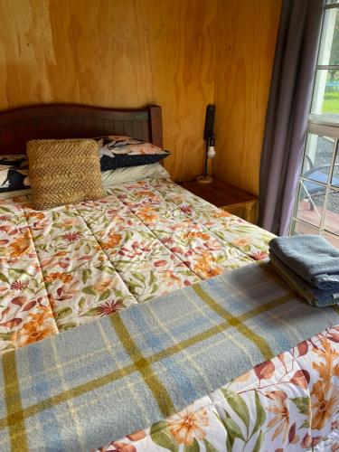 a bed with a quilt on it in a bedroom at Waitomo Farmstay - Kiwi Cabin 5 in Waitomo Caves
