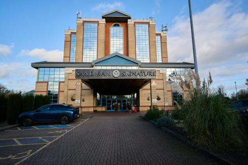 a building with a car parked in front of it at Sandman Signature London Gatwick Hotel in Crawley