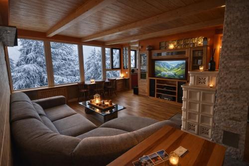 a living room with a large couch and a tv at Chalet DolceVista con SPA, vicino a Cortina d'Ampezzo in Borca di Cadore