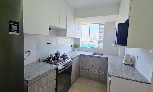 a white kitchen with a stove and a window at Sumaran II in Lima