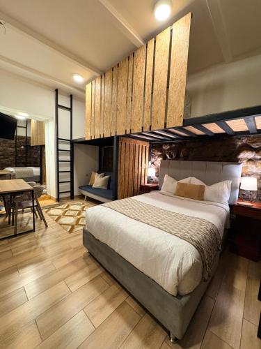 a bedroom with a large bed and a dining room at Blacky Hostel and Apartments in Cusco