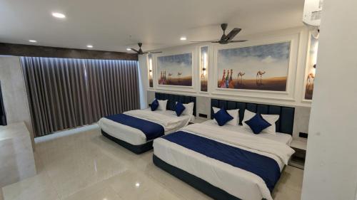 a bedroom with two beds with blue pillows at Hotel Crown in Dwarka