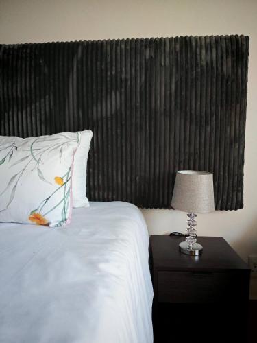 a bed with a pillow and a lamp on a table at King Deluxe Cottage Room in Cape Town