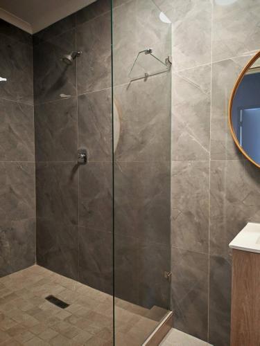 a shower with a glass door in a bathroom at Stylish Studio Room with Shared Pool Near Table View Beach in Cape Town
