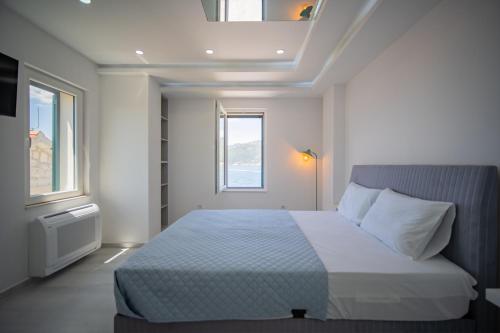 a bedroom with a bed and two windows at Caelum Et Mare in Donja Lastva