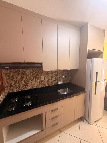 a kitchen with white cabinets and a sink and a refrigerator at Casa de hóspedes in Canoas