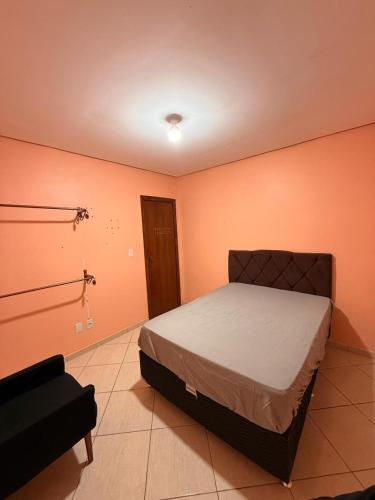 a bedroom with a bed in a room with orange walls at Casa de hóspedes in Canoas