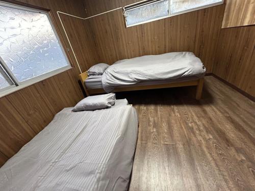 a small room with two beds and a window at Seven base Yoshiumi in Imabari