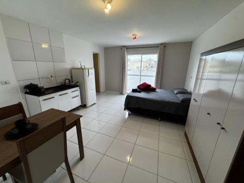a bedroom with a bed and a kitchen with a table at SJ Suites in São José dos Pinhais