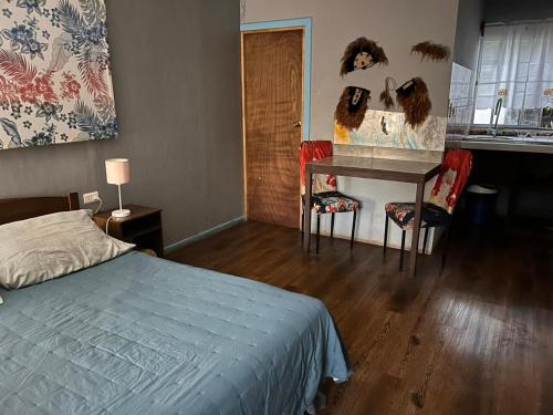 a bedroom with a bed and a desk with a mirror at Hospedaje henua roa 2 in Hanga Roa