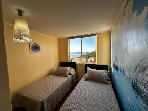 two beds in a room with a window at Laguna del Mar, C 208 in La Serena