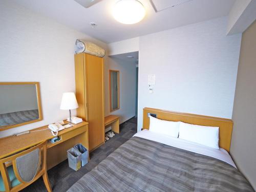 a hotel room with a bed and a desk at Hotel Route-Inn Sapporo Shiroishi in Sapporo