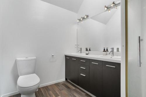a bathroom with a toilet and a sink and a mirror at Tangaroa Beachside Bliss - with Private Pool in Whangamata