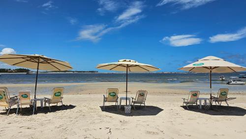 a group of chairs and umbrellas on a beach at Studio Beira-Mar na Praia dos Carneiros in Tamandaré