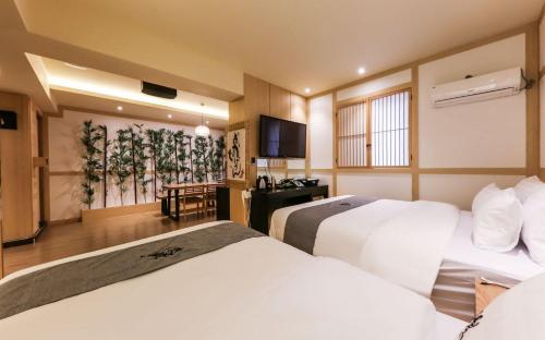a hotel room with two beds and a television at Manwol Hotel in Ŭmnae