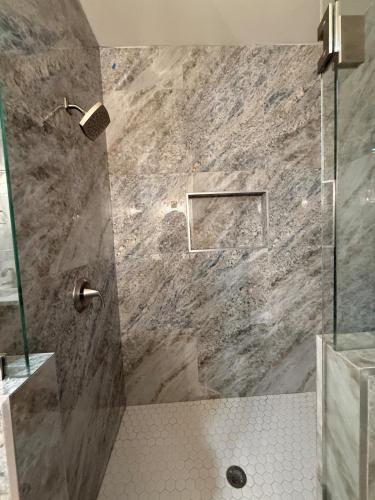 a bathroom with a shower with a stone wall at Dream Casa Blanca in Harlingen