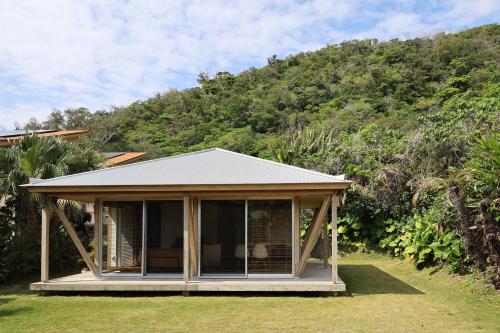 a gazebo in the grass with a mountain at SHINMINKA Villa UTTABARU in Amami