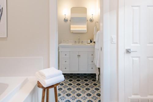 a white bathroom with a sink and a stool with towels at Lithia Springs Resort in Ashland