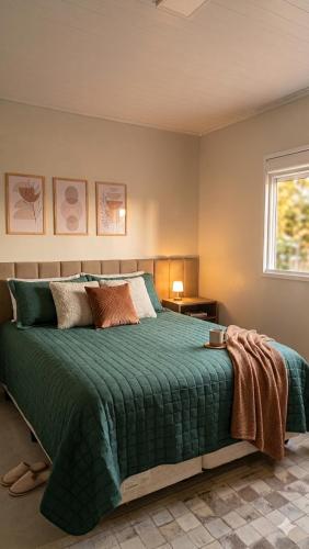 a bedroom with a bed with a green comforter at Casa Nova com 3 quartos in São Gabriel