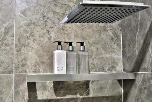 two bottles ofodorizers sitting on a shelf in a bathroom at Cozier Glitz in Cape Town