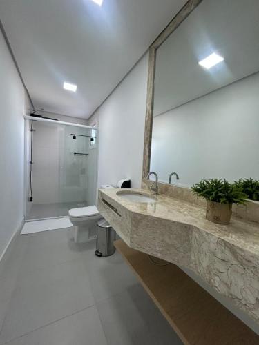 a bathroom with a sink and a toilet and a mirror at Esplendor Residence Seu Paraíso em Atlântida com Piscina in Xangri-lá