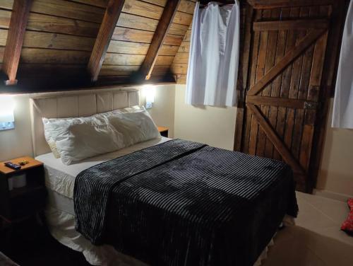a bedroom with a bed and a wooden door at Chalés FRONT LAKE 1 in Córrego do Bom Jesus