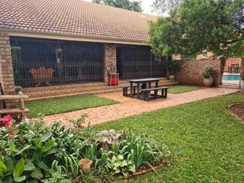 a garden with a picnic table and a bench at Chandané Guesthouse in Thabazimbi