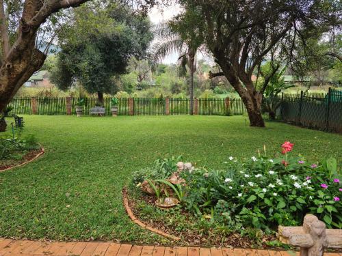a park with a fence and a garden with flowers at Chandané Guesthouse in Thabazimbi