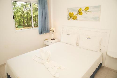 a white bedroom with a bed and a window at Pé na areia - verdadeiro paraíso em Muro Alto in Porto De Galinhas