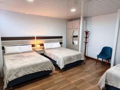 a bedroom with two beds and a blue chair at Cusco Center Apartment in Cusco