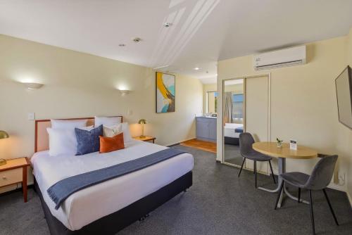 a hotel room with a bed and a table and chairs at Daffodil Apartments in Christchurch
