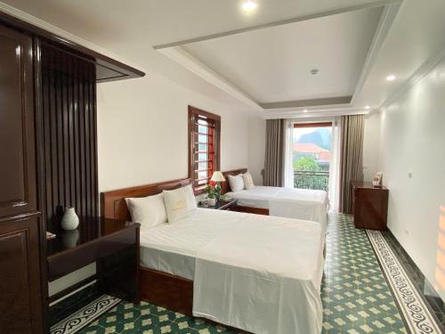 a hotel room with two beds and a window at Champs De Tam Coc Hotel in Vũ Lâm