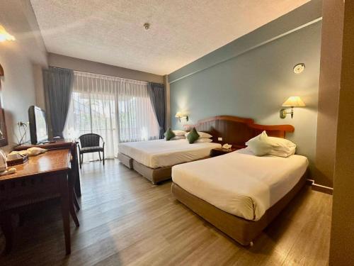 a hotel room with two beds and a desk at Chiangmai Gate Hotel in Chiang Mai