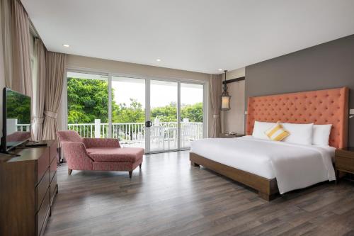 a bedroom with a large bed and a balcony at Premier Villa Resort Danang in Danang