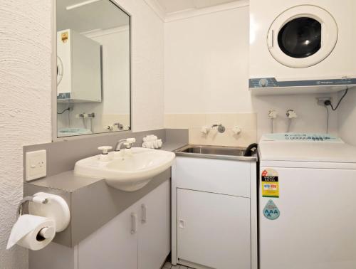 a small bathroom with a sink and a refrigerator at Parkwood 6 - 2BR Split Lvl Apartment l Spa Bath l BBQ l Central Location in Jindabyne
