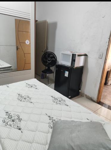 a bedroom with a bed and a microwave on a refrigerator at Casa da nicinha in Vitória