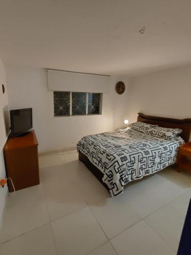 a bedroom with a bed and a television in it at Posada San Jorge in Pacho