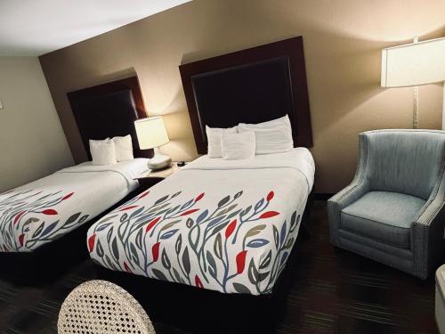 a hotel room with two beds and a chair at Trident Inn & Suites New Orleans in New Orleans