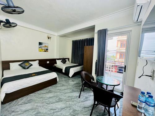 a hotel room with two beds and a glass table at Đại Việt Hotel in Làng Liễu