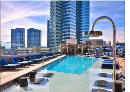 a large swimming pool with lounge chairs and a city skyline at Stay Together Suites - Stunning Penthouse On The Strip Sleeps 16 - NO RESORT FEE in Las Vegas