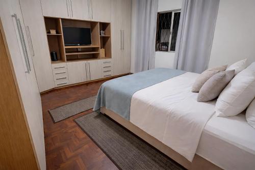 a bedroom with a white bed and a television at Flat Completo - Cozinha - Lavadora - Climatizado in Erval dʼOeste