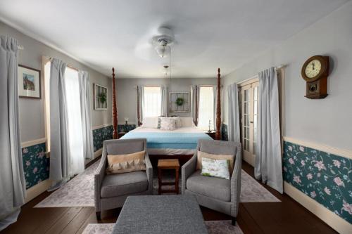 a bedroom with a bed and two chairs and a clock at Historic Rider's Hostelry in Painesville