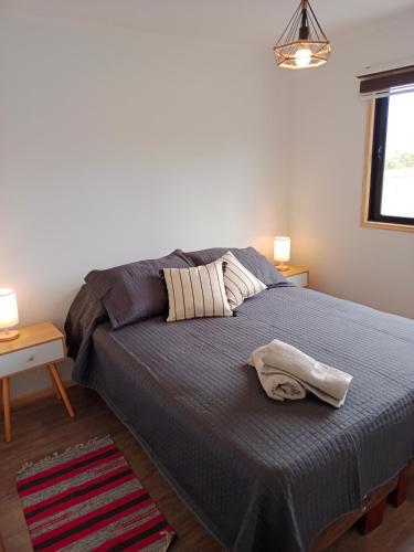 a bedroom with a bed and two tables and a window at Cabañas Lodge el Mauco in Curacaví