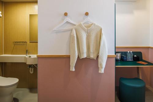a white sweater is hanging on a rack in a bathroom at mu petite in Ipoh